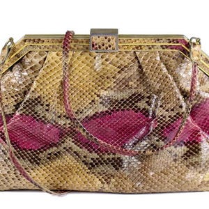 Peut inclure: Une pochette vintage en peau de serpent avec une fermeture dorée et un motif rose et brun.