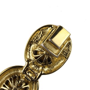 Puede incluir: Pulsera de metal dorado con un dise&ntilde;o detallado. La pulsera tiene un cierre que se ve en la imagen.