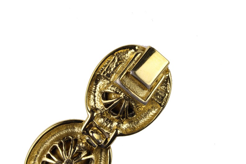 Puede incluir: Pulsera de metal dorado con un dise&ntilde;o detallado. La pulsera tiene un cierre que se ve en la imagen.
