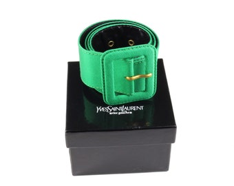 Pode incluir: Um cinto de cetim verde com uma fivela dourada e as palavras "Yves Saint Laurent rive gauche" na caixa.