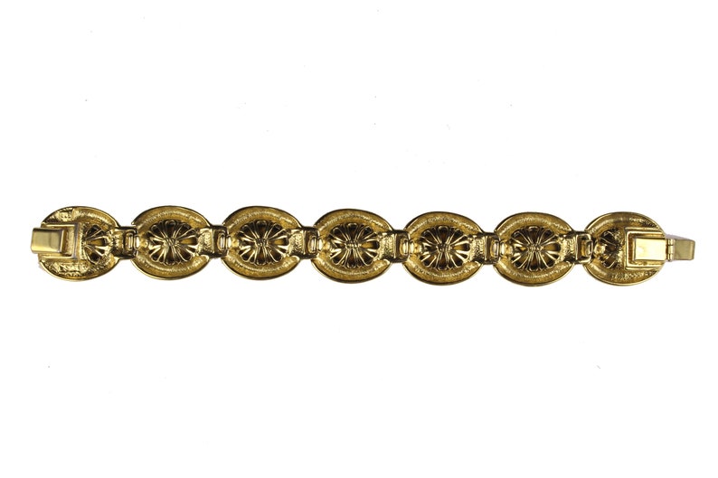 Puede incluir: Un brazalete dorado con un dise&ntilde;o de cadena de eslabones con eslabones ovalados con un patr&oacute;n decorativo.
