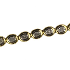 Puede incluir: Un brazalete de oro con piedras transparentes de forma ovalada engastadas en el centro de cada eslab&oacute;n.