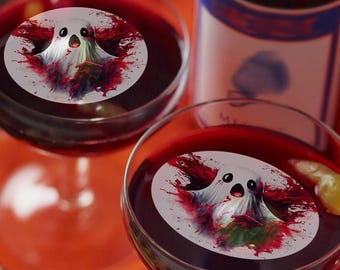 May include: Two stemmed glasses filled with a deep red liquid, each with a white ghost-shaped image. The glasses sit on an orange surface, with a bottle in the background. Halloween-themed cocktail.