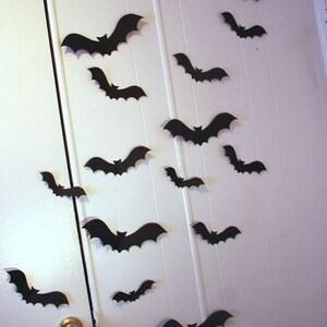 May include: A white door decorated with black paper bats for Halloween. The bats are of various sizes and are arranged in a random pattern.