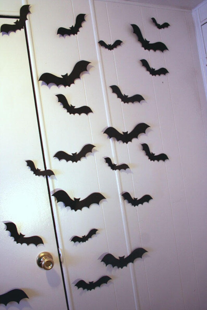May include: A white door decorated with black paper bats for Halloween. The bats are of various sizes and are arranged in a random pattern.