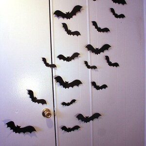 May include: A white door and wall decorated with black paper bats for Halloween.