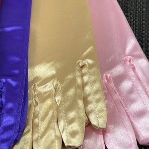 May include: Three pairs of satin gloves in purple, gold, and pink. The gloves are folded and arranged in a row.