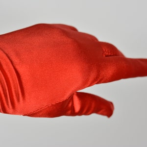 May include: A pair of long, red satin gloves. The gloves are smooth and have a slight sheen.