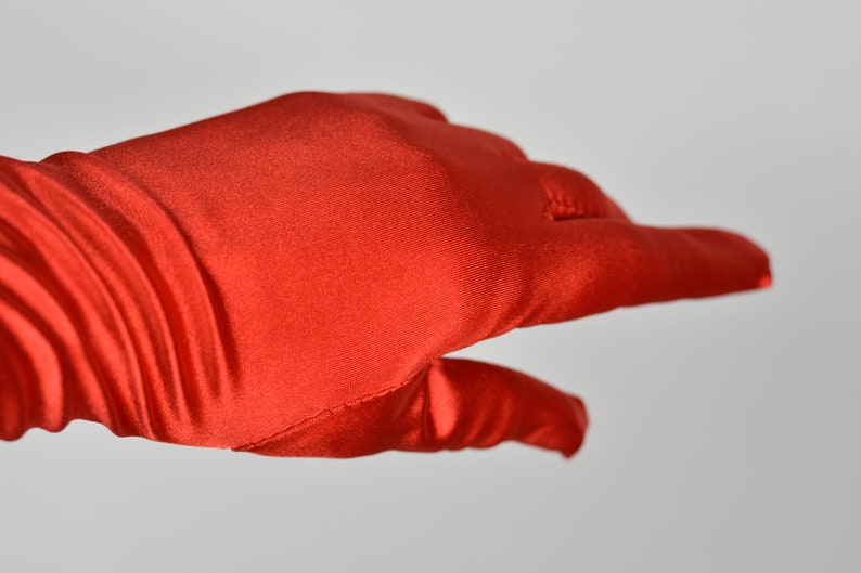 May include: A pair of long, red satin gloves. The gloves are smooth and have a slight sheen.