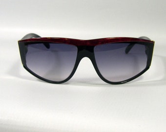 May include: A pair of red and black sunglasses with a gradient lens. The sunglasses have a unique, angular shape.