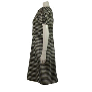 Puede incluir: Un vestido de cuadros vichy blanco y negro con mangas cortas y un estilo de manga ligeramente abullonado. El vestido tiene un corpi&ntilde;o ajustado y una falda ligeramente acampanada.
