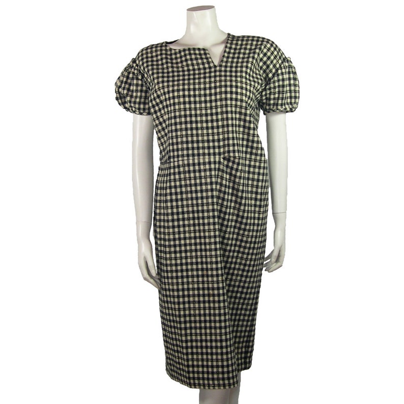 Puede incluir: Un vestido midi de cuadros vichy blanco y negro con cuello en V y mangas cortas abullonadas.