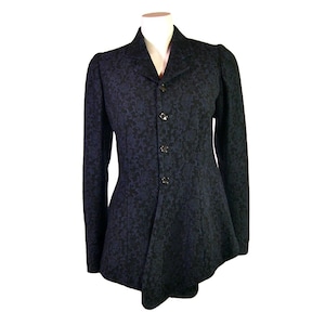 May include: A black and blue patterned jacket with a fitted waist and a slightly flared hem. The jacket has a collar and five buttons down the front.