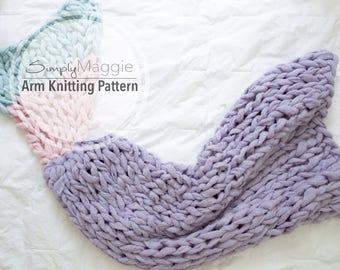 Op de afbeelding: Een arm breipatroon voor een dekentje in de vorm van een zeemeerminstaart, in lavendel, roze en blauw. De tekst "Simply Maggie Arm Knitting Pattern" is zichtbaar op de deken.