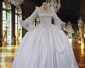 May include: A white ball gown with a ruffled neckline and long sleeves. The gown is made of a soft, flowing fabric and has a full skirt. The gown is photographed in a grand, ornate setting.