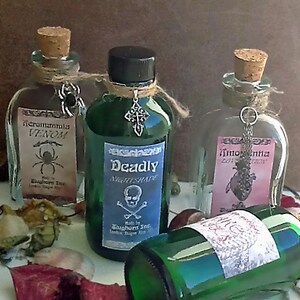 K&ouml;nnte beinhalten: Dekorative Flaschen mit Korken und Anh&auml;ngern. Die Flaschen sind mit den W&ouml;rtern "Venom", "Deadly Nightshade" und "Lotion" beschriftet. Die Flaschen enthalten gr&uuml;ne und klare Fl&uuml;ssigkeiten. Die Flaschen sind mit Schnur gebunden.