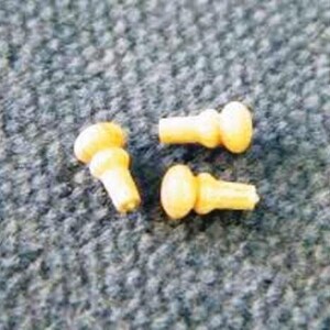 Könnte beinhalten: Drei kleine, gelbe Holz-Knöpfe mit abgerundeter Oberseite und einem kleinen, zylindrischen Sockel.