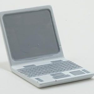 May include: A miniature laptop figurine featuring a glossy white frame and a solid gray screen. The keyboard area includes a detailed gray keypad layout with a central trackpad and two distinct buttons, all rendered in a smooth, reflective finish.