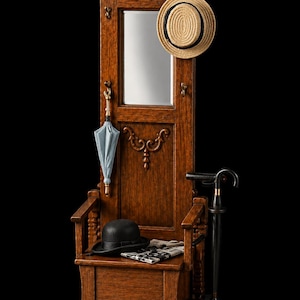 Puede incluir: Miniatura de recibidor de madera con espejo, sombrero, paraguas y bastón. El recibidor es marrón con tallas decorativas. Un sombrero de paja cuelga del espejo y un bombín negro está en el banco. También hay un paraguas y un bastón en miniatura.