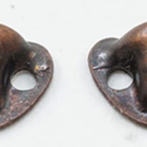 May include: Two small, oval-shaped metal drawer pulls with a dark copper finish. Each pull features a raised, rectangular center section and two circular screw holes on the flat, extended sides for mounting to a surface or furniture piece.