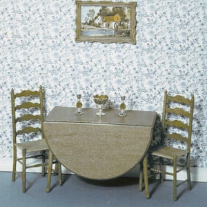 Puede incluir: Una mesa de madera con una hoja abatible y dos sillas de madera. La mesa está puesta con un cuenco de fruta y dos vasos. Las sillas son sencillas y robustas. La mesa y las sillas están en una habitación con papel tapiz floral.