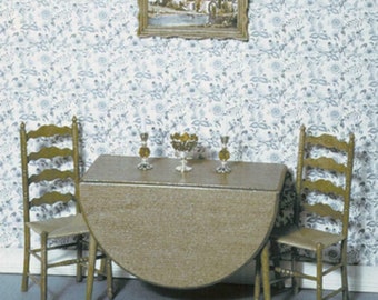 May include: A wooden table with a drop leaf and two wooden chairs. The table is set with a bowl of fruit and two glasses. The chairs are simple and sturdy. The table and chairs are in a room with a floral wallpaper.