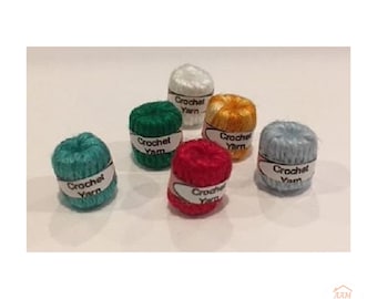 May include: Six miniature balls of crochet yarn in teal, dark green, white, red, orange, and light blue. Each small yarn ball is wrapped with a white paper label featuring the black text Crochet Yarn printed on the front of the band.