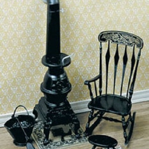 May include: Miniature black stove with a chimney, a rocking chair, a small stool, a bucket, and a shovel. The stove sits on a decorative mat. The rocking chair has a detailed back. The scene is set against a patterned wallpaper.