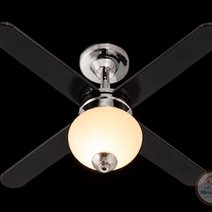 Puede incluir: Ventilador de techo en miniatura con cuatro aspas negras y acabado cromado. El ventilador tiene una lámpara redonda de vidrio esmerilado en el centro. El ventilador está diseñado para una casa de muñecas o un entorno en miniatura.