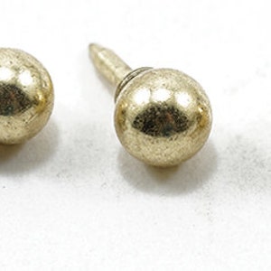 May include: Three gold-toned metal tacks with round heads and pointed tips.
