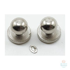 May include: Two silver-toned metal ball-shaped studs with flat circular bases and one small oval-shaped metal eyelet component. The image includes a small logo in the bottom right corner with the text AAM All About Miniatures.