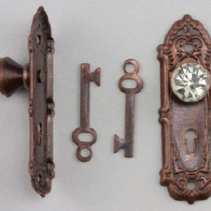 Könnte beinhalten: Antikes Türbeschlag-Set in Kupfer-Finish mit einem Kristall-Türknopf, einem Schlüsselloch und zwei Skelettschlüsseln.