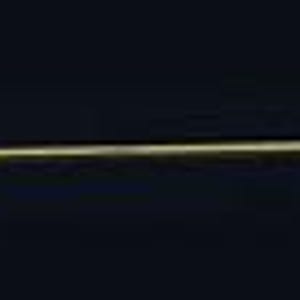 May include: A long, slender gold-toned hat pin featuring a circular head with an ornate, decorative filigree base. The centre of the circular head displays a detailed, embossed starburst or floral pattern, providing a textured finish to the metal.