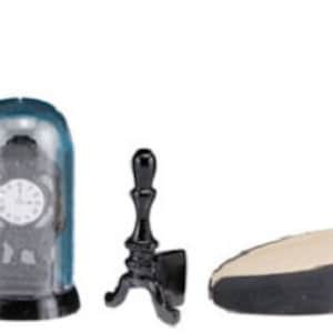 Puede incluir: Conjunto de cinco accesorios de chimenea de metal negro, que incluyen un reloj en una cúpula de vidrio, un soporte con tres patas, un soporte con dos patas y un soporte con cuatro patas.