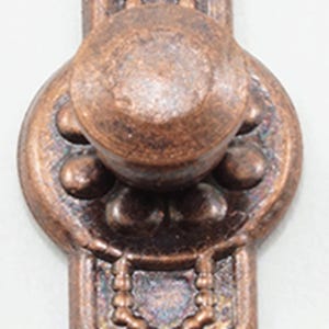 May include: A copper-toned metal drawer pull featuring an elongated vertical design with a central circular knob, beaded detailing, and two mounting holes at the top and bottom. The surface has a textured, weathered finish with dark accents.