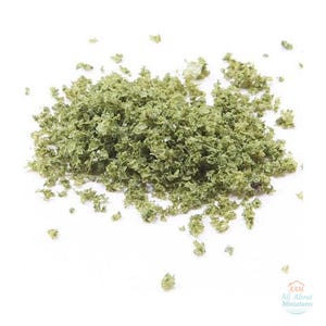 May include: A pile of small, textured, light green foliage flakes used for miniature modeling. The flakes have an irregular, crinkled appearance and are scattered across the surface. The logo AAM All About Miniatures is visible.