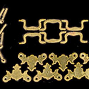 May include: A collection of gold-toned metal hardware components including several small screws, four curved drawer pull handles, and six decorative triangular backplates with circular mounting holes, all arranged against a black background.