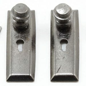 May include: Two rectangular dark metallic escutcheon plates, each featuring a central keyhole and a cylindrical knob at the top. Two matching small, flat, silver-toned skeleton keys are positioned on the outer sides of the plates.