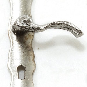 May include: A silver door handle with a decorative backplate and a curved lever. The handle has a keyhole.