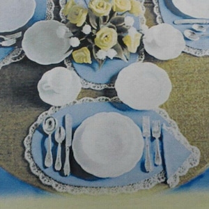 May include: A table setting with white plates, cups, and silverware on blue placemats with a lace trim. A bouquet of yellow roses sits in the center. The table is set for a formal meal.