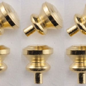 May include: Six gold-toned metal cabinet knobs with a round top and a small, round base. The knobs have a smooth, shiny finish.