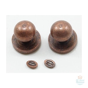 May include: Two copper-colored metal knobs with spherical tops and circular bases, accompanied by two small, oval-shaped metal washers. The hardware features a weathered, textured finish and includes the text AAM All About Miniatures.