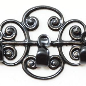 May include: A black metal wall hook rack featuring three individual hooks attached to a horizontal bar. The frame is decorated with symmetrical, ornate scrollwork patterns that extend outward from the center, creating a continuous design.