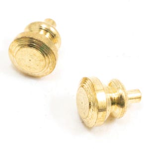 May include: Two small, round, metallic gold-colored knobs with a polished finish. Each knob features a flat circular top surface, a tiered side profile with concentric ridges, and a short cylindrical post extending from the base for mounting.