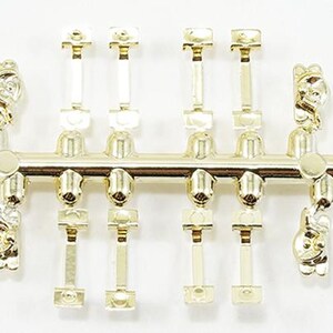 May include: A gold-colored plastic sprue containing four small, molded animal-shaped charms and several rectangular connector pieces. The central horizontal bar connects the individual components, which feature a shiny, reflective metallic finish.