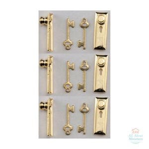 May include: A set of three miniature gold-toned hardware kits, each containing a door handle, two distinct keys, and a rectangular escutcheon plate with a keyhole. The text AAM All About Miniatures is visible in the bottom right corner.