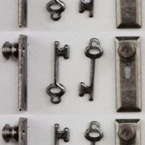 Könnte beinhalten: Drei Sätze Miniatur-Türbeschläge, jedes Set enthält einen Türknauf, eine Türplatte und zwei Schlüssel. Die Beschläge sind aus Metall und haben eine silberne Oberfläche.