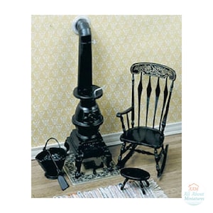 May include: A miniature black cast iron style stove with a tall chimney pipe, a matching black rocking chair with a decorative backrest, a small black footstool, and a black coal bucket with a shovel, all designed for dollhouse display.