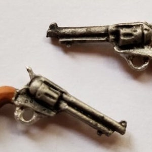 May include: Two miniature silver-colored toy revolvers with brown plastic handles.