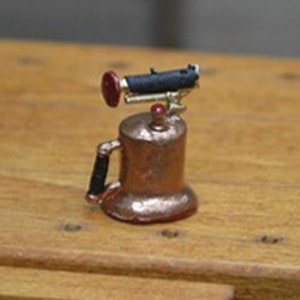 May include: A miniature copper-colored antique-style telephone with a black receiver and a red button on the top.